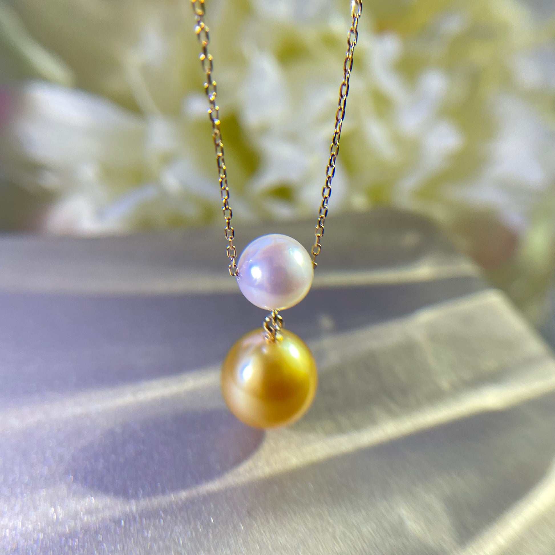 18k gold necklace with Akoya and southsea gold pearl on light gold background