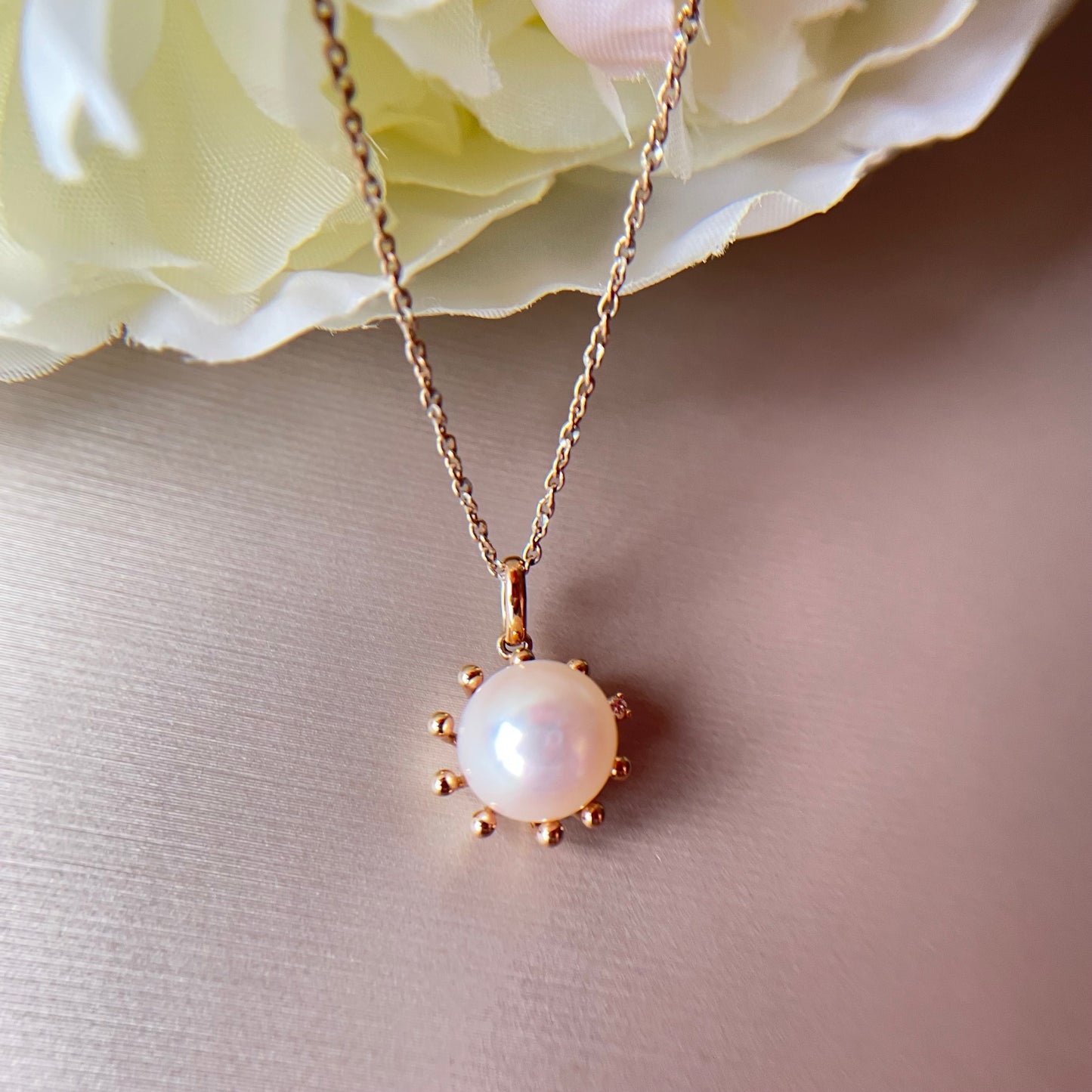 Pearl necklace with gold chain on a soft background.