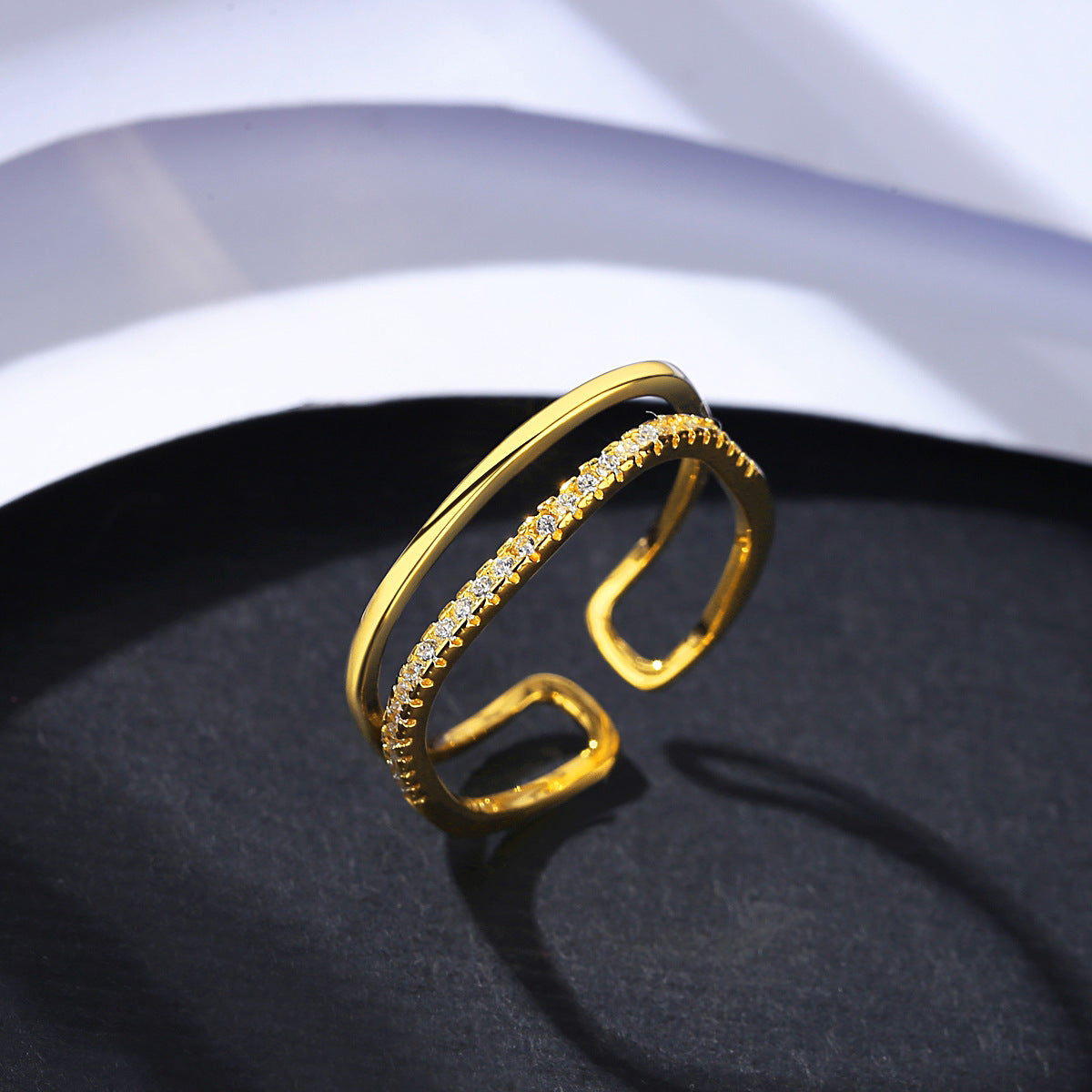 Gold ring with zirconia accents on a dark surface.