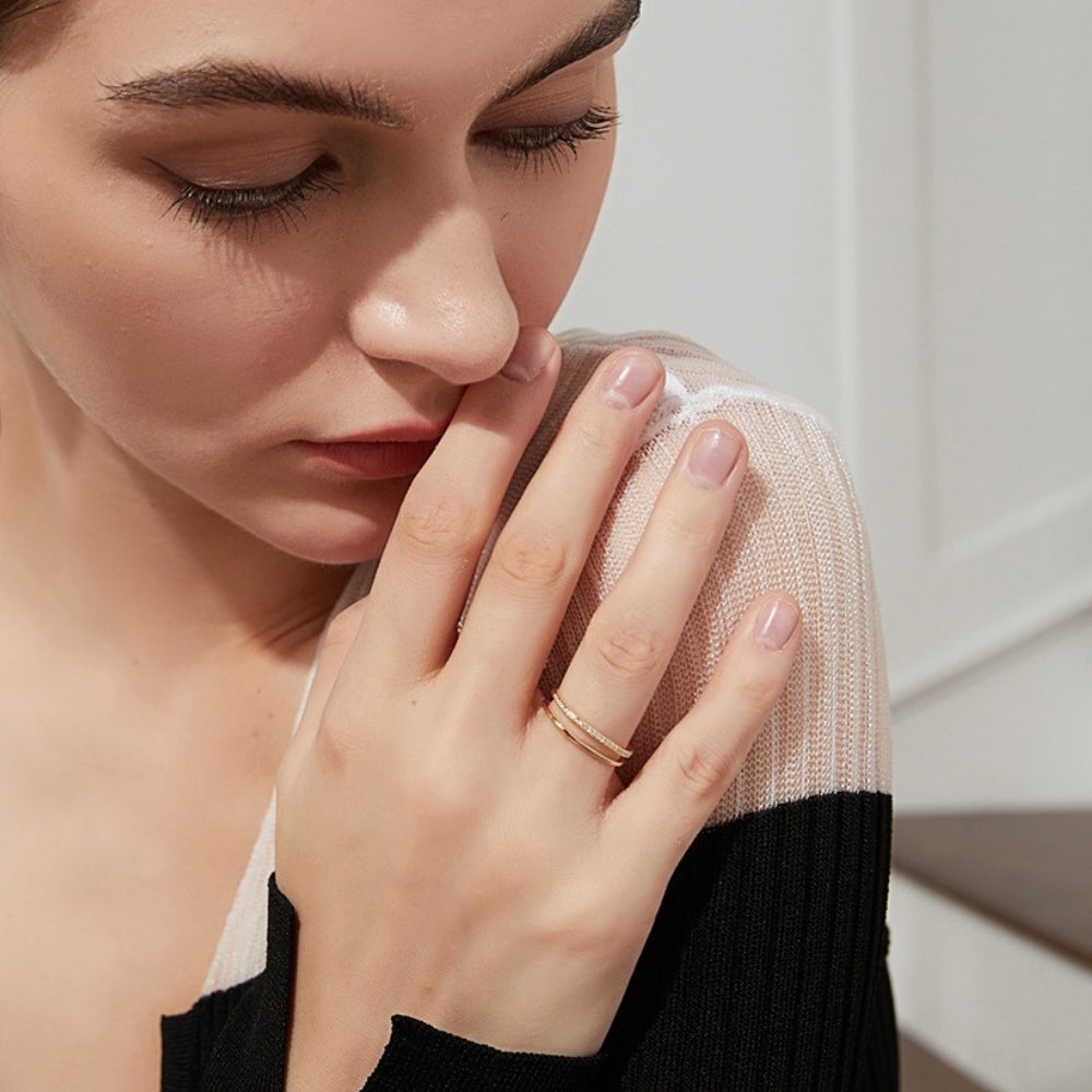 Woman wearing a gold color ring on her finger with a neutral background.