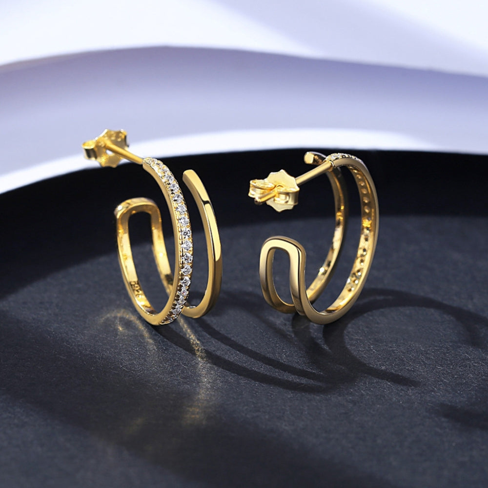 Gold hoop earrings with zirconia on a dark surface