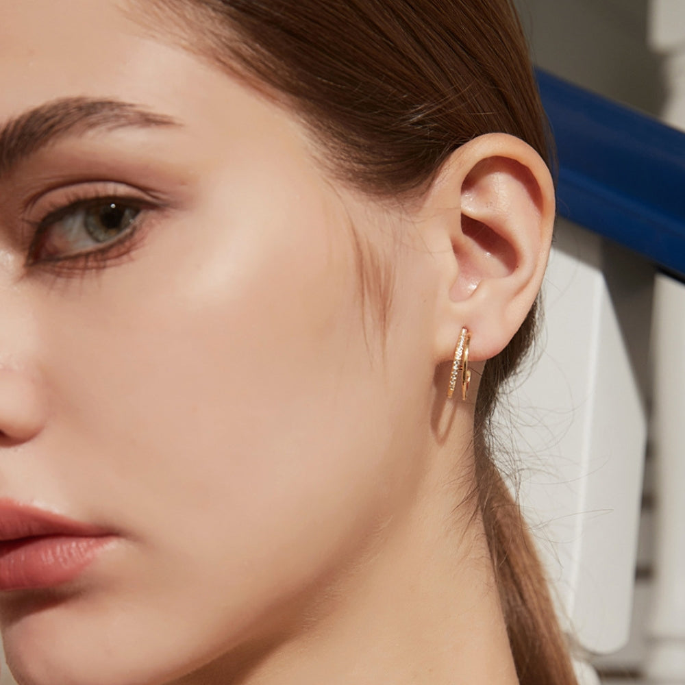 Close-up of a woman wearing gold hoop earrings with zirconia.