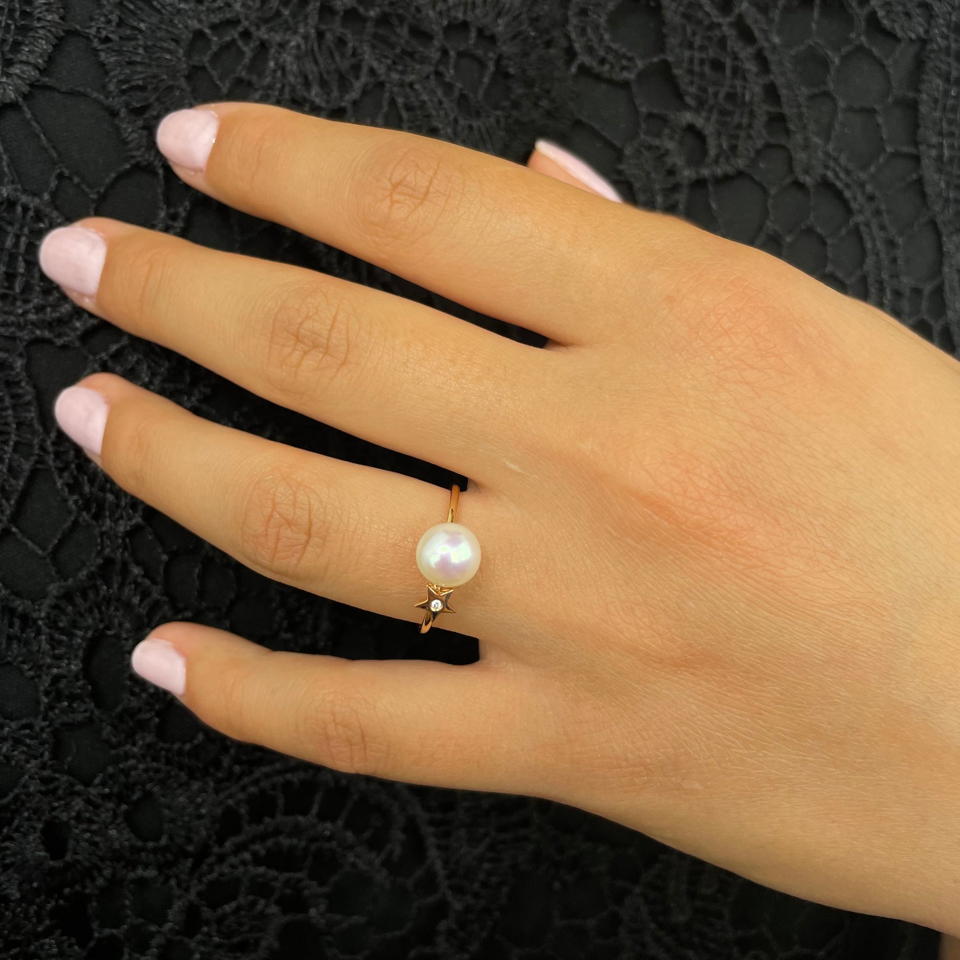 Hand wearing a Akoya pearl diamond ring on a black lace clothes