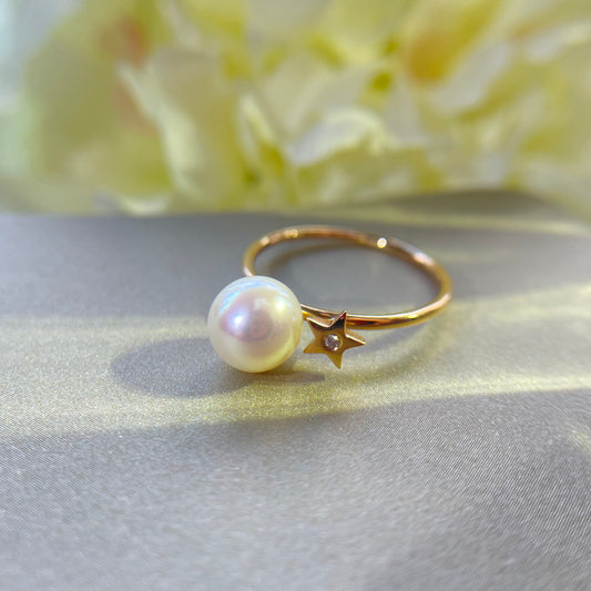 Gold ring with Akoya pearl and diamond on gold surface with a yellow floral background