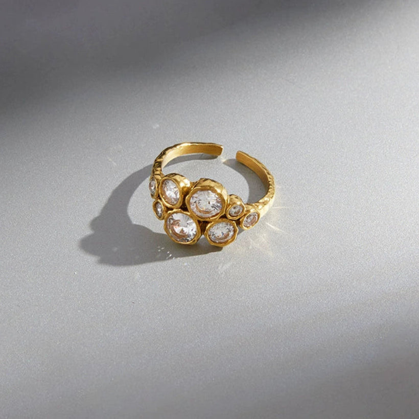 A gold adjustable ring with a cluster of clear round zirconia from SKADIS Jewelry
