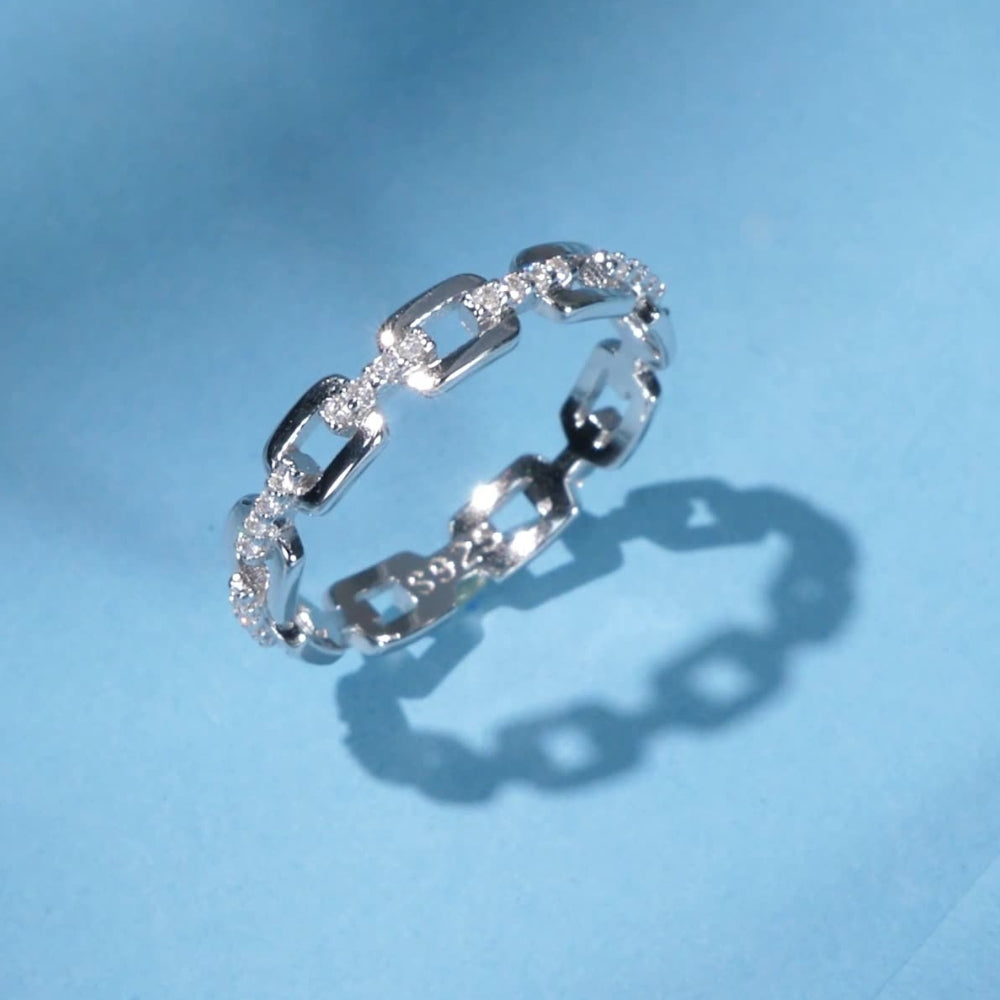 Silver chain link ring on a light blue background.
