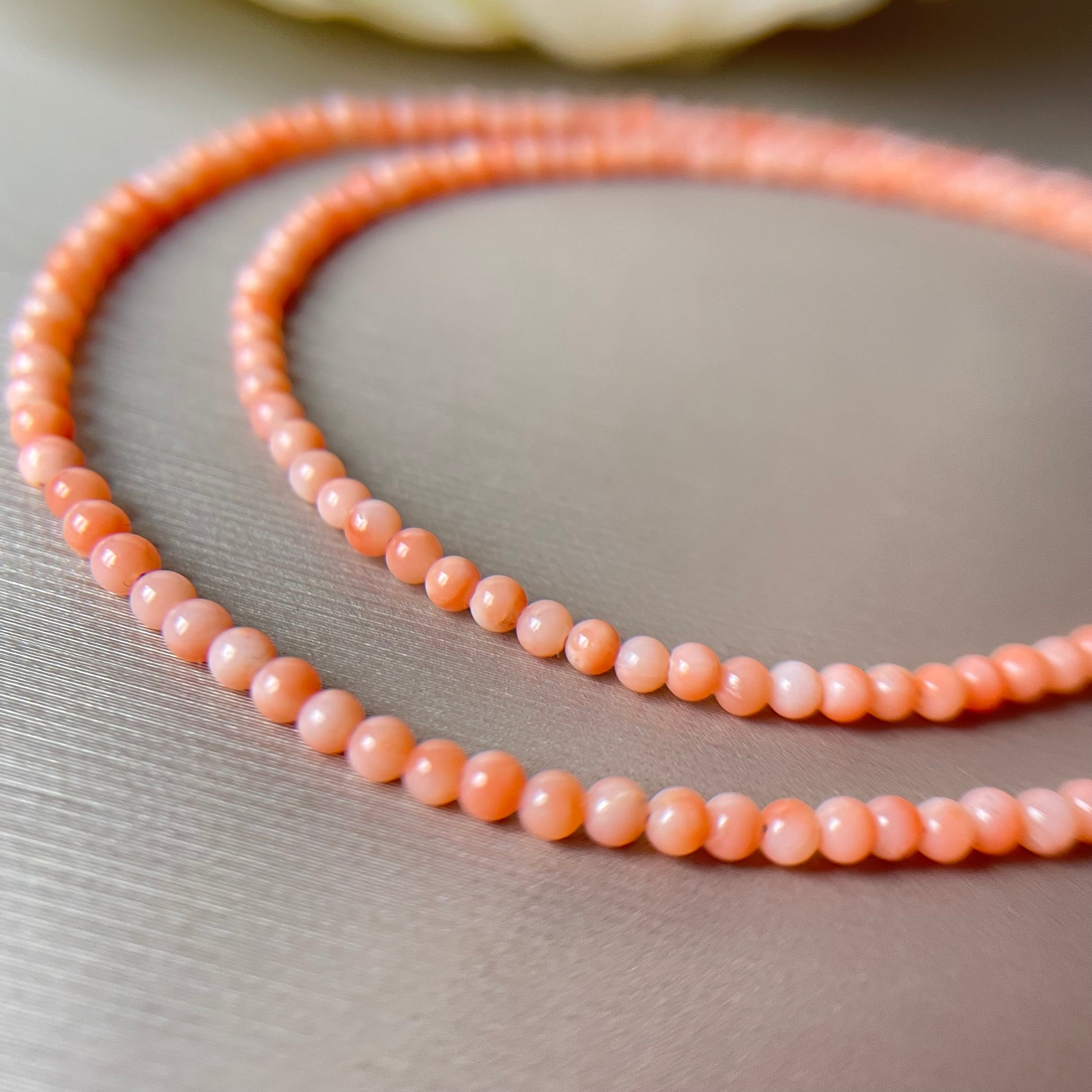Coral necklace with peach-colored beads on a neutral background.