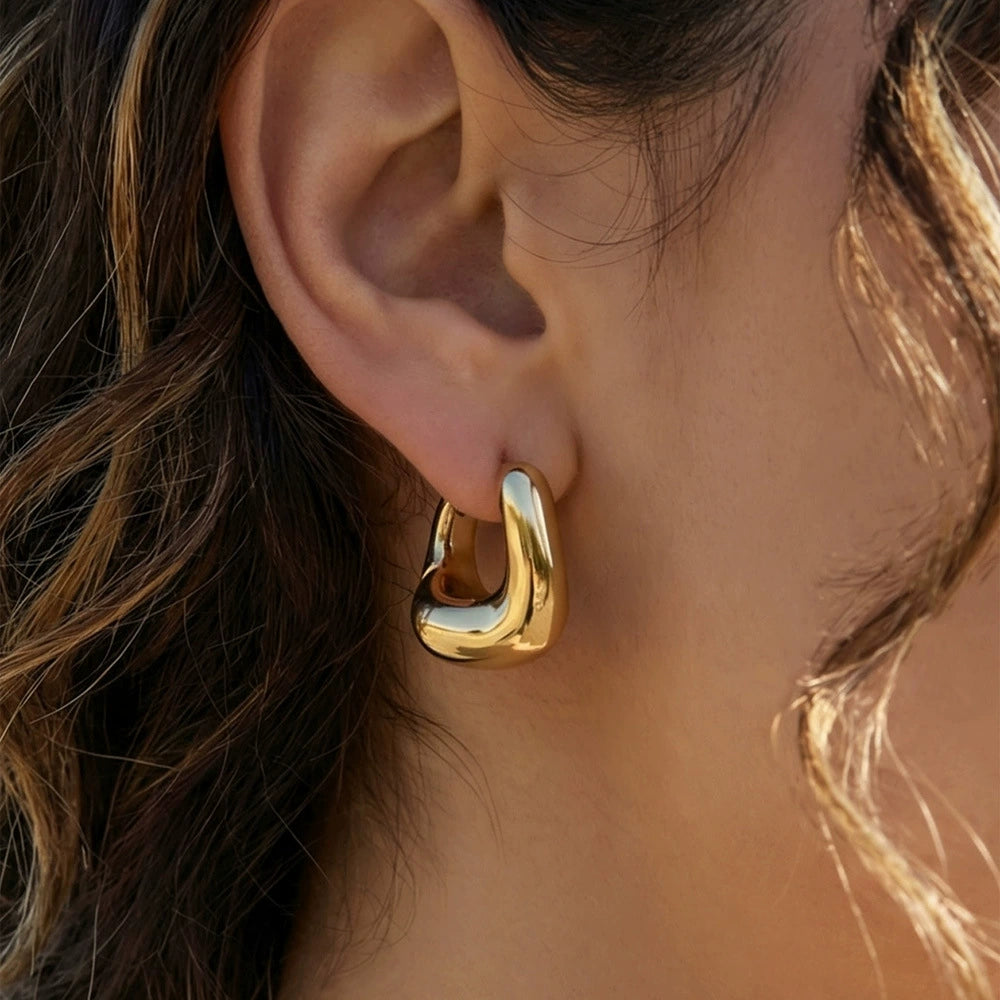 Close-up of a person wearing a gold-plated hoop earring from SKADIS Jewelry.