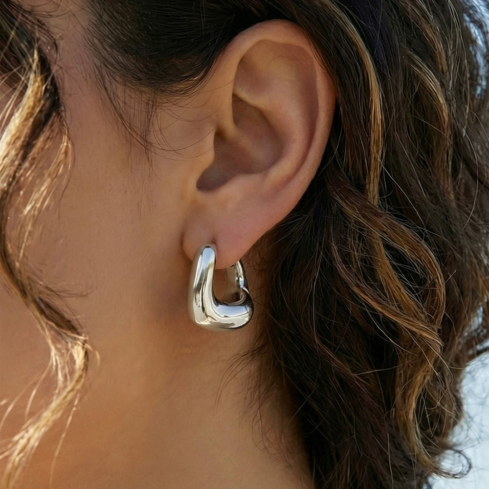 Close-up of a person wearing a silver hoop earring from SKADIS Jewelry.