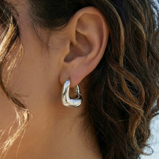 Close-up of a person wearing a silver hoop earring from SKADIS Jewelry.