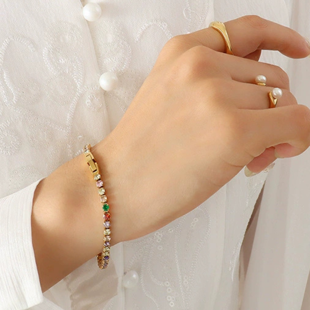 Hand wearing a gold bracelet with colorful zirconia from SKADIS Jewelry