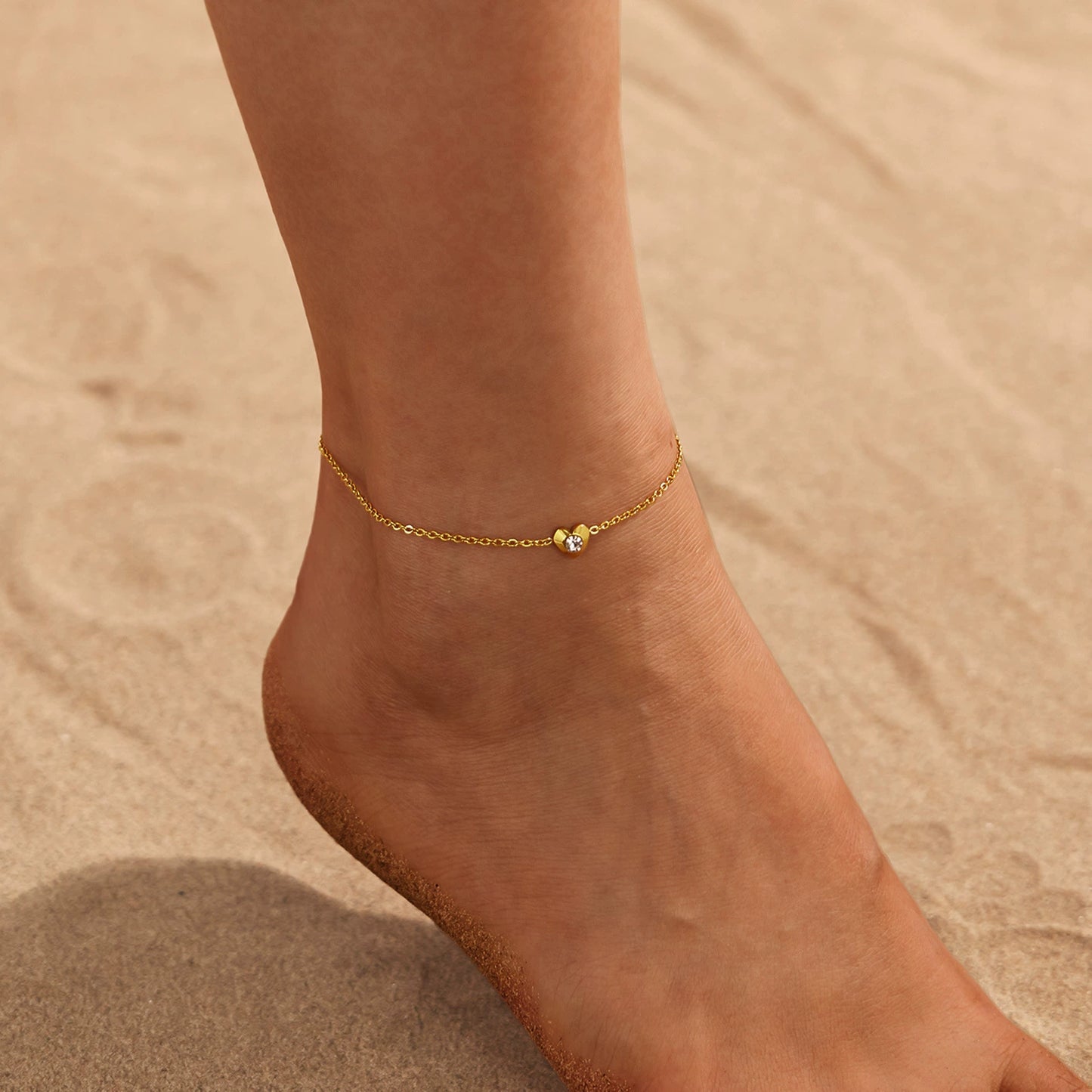 Gold anklet with heart on a foot from SKADIS Jewelry