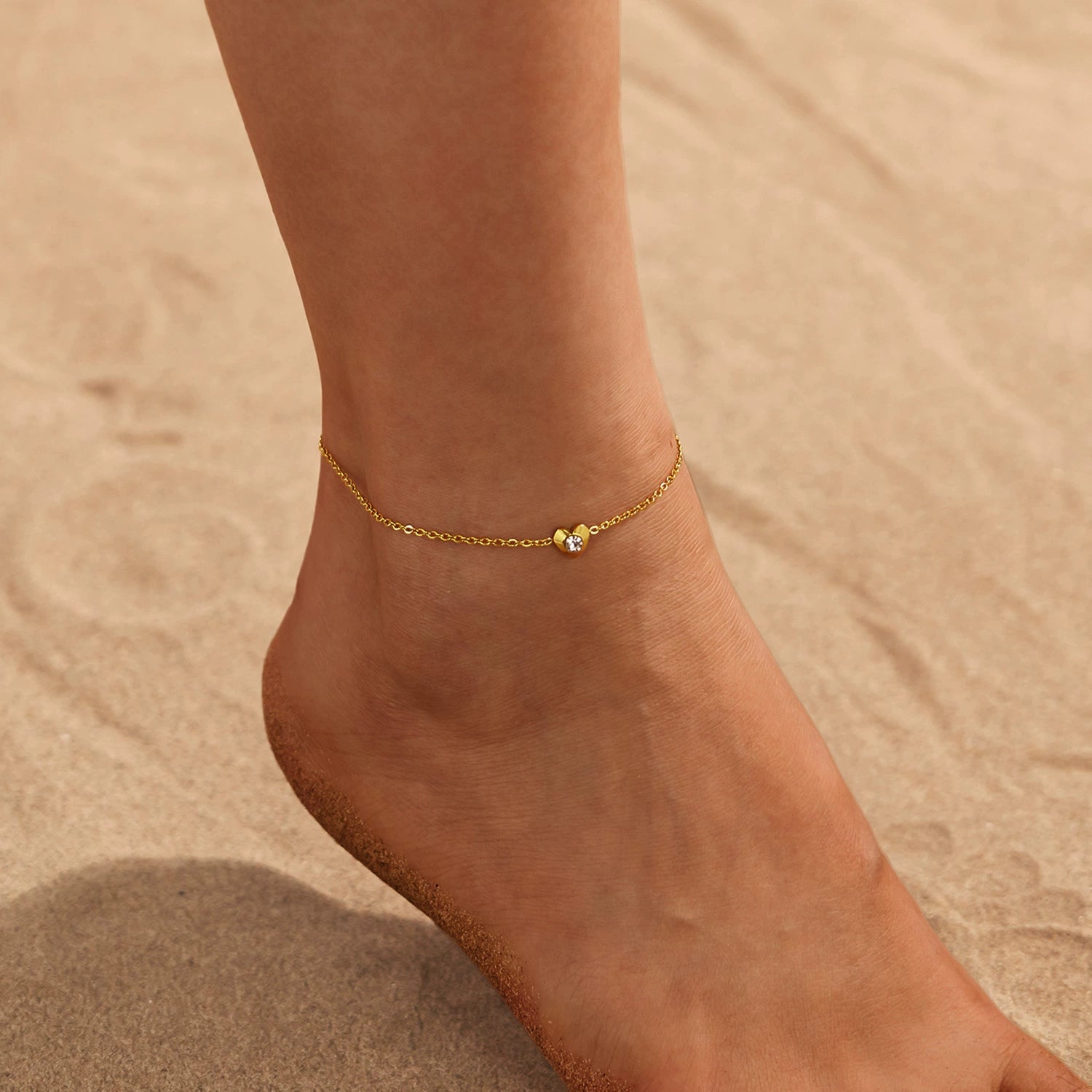 Gold anklet with heart on a foot from SKADIS Jewelry