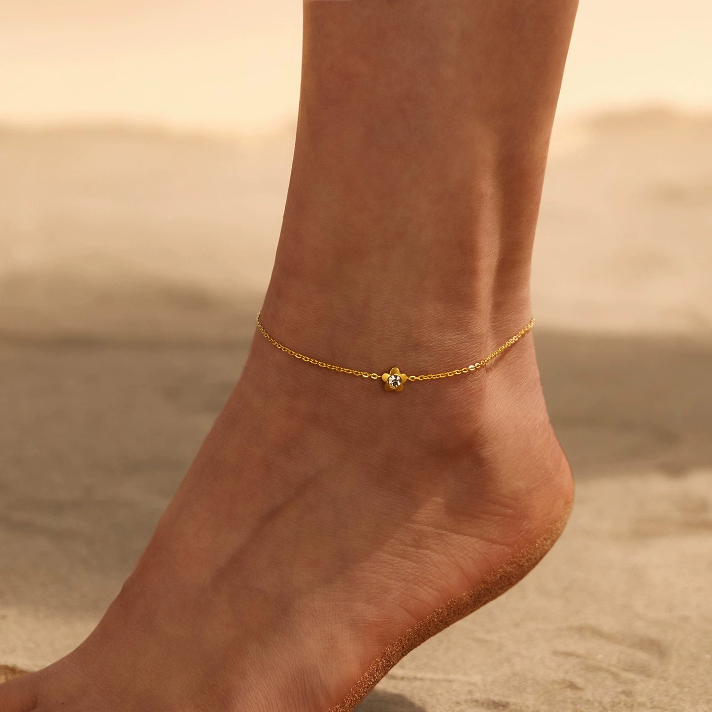 Gold anklet with flower on a foot from SKADIS Jewelry