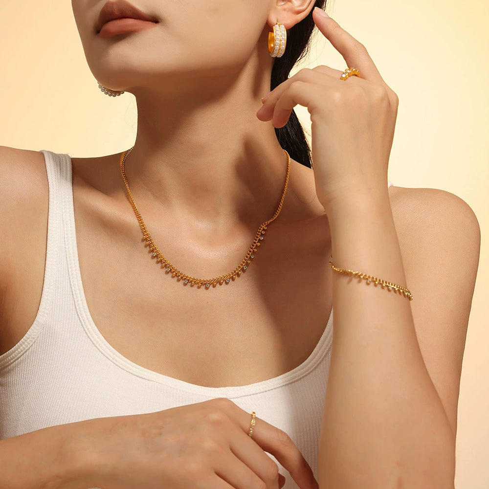 A woman wearing gold jewelry including a necklace, earrings, and bracelet from SKADIS Jewelry
