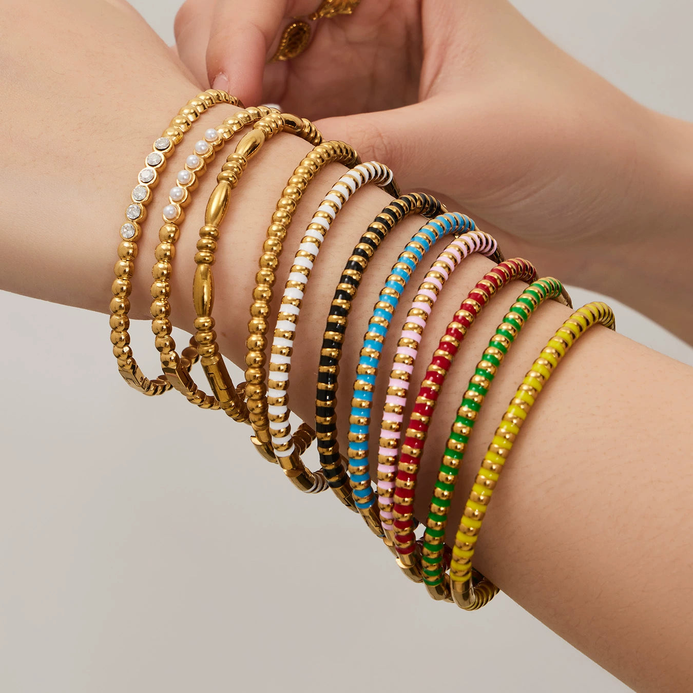 Hand wearing multiple colorful bangles from SKADIS Jewelry