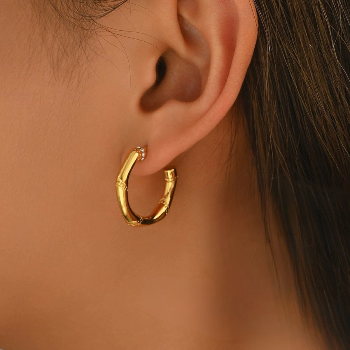 Gold hoop earring worn on a model from SKADIS Jewelry