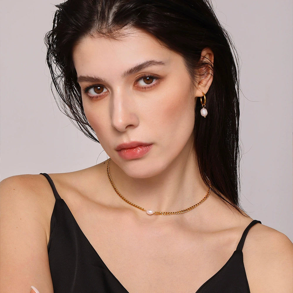 Model wearing a black top and gold necklace with pearl from SKADIS Jewelry