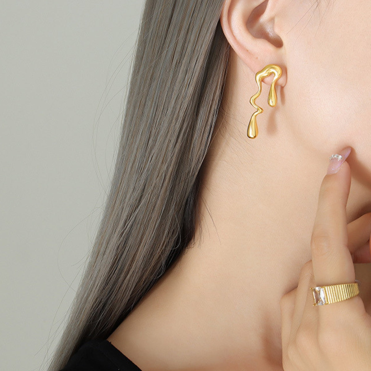 Gold earring worn by a person from SKADIS Jewelry