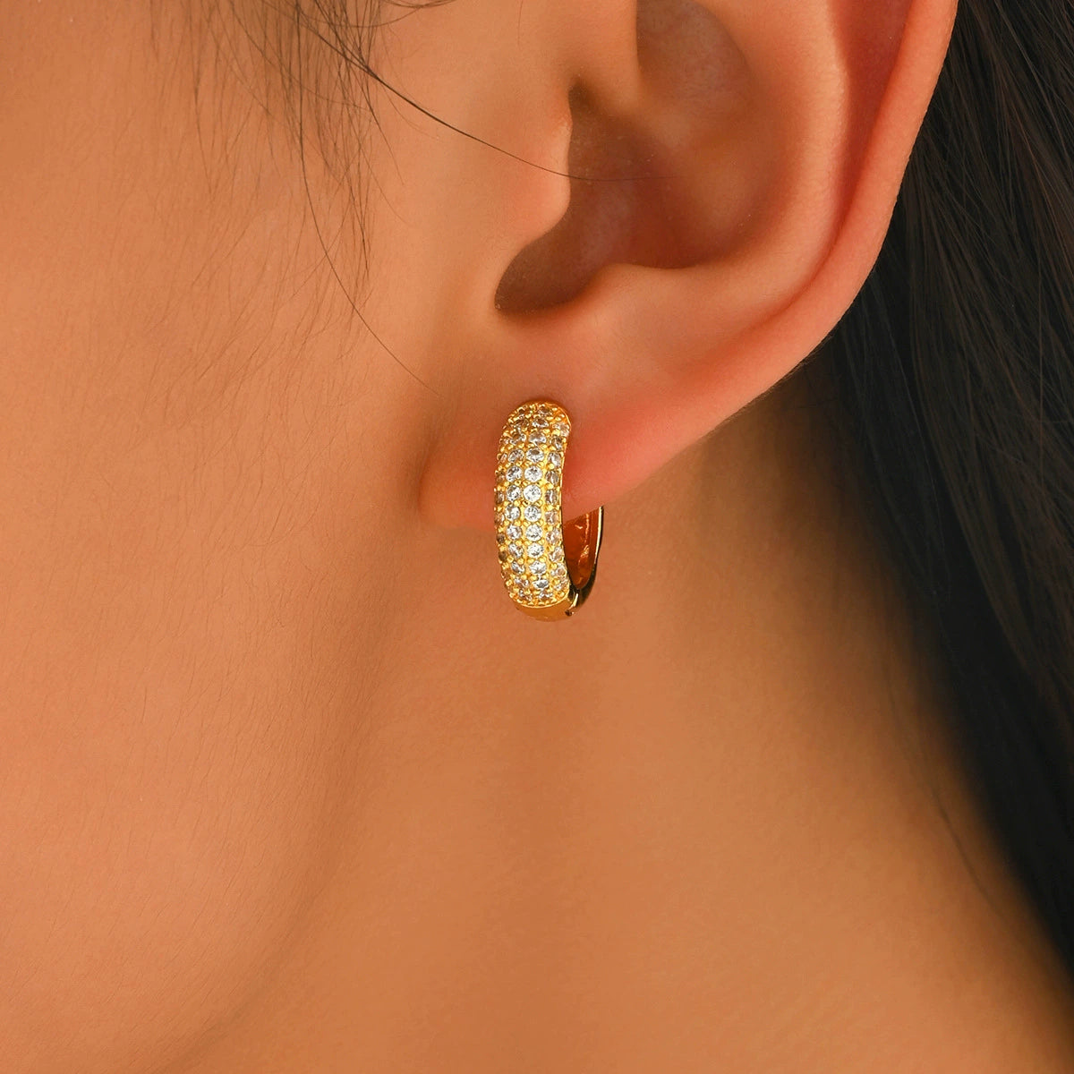 Gold hoop earring worn by a person from SKADIS Jewelry