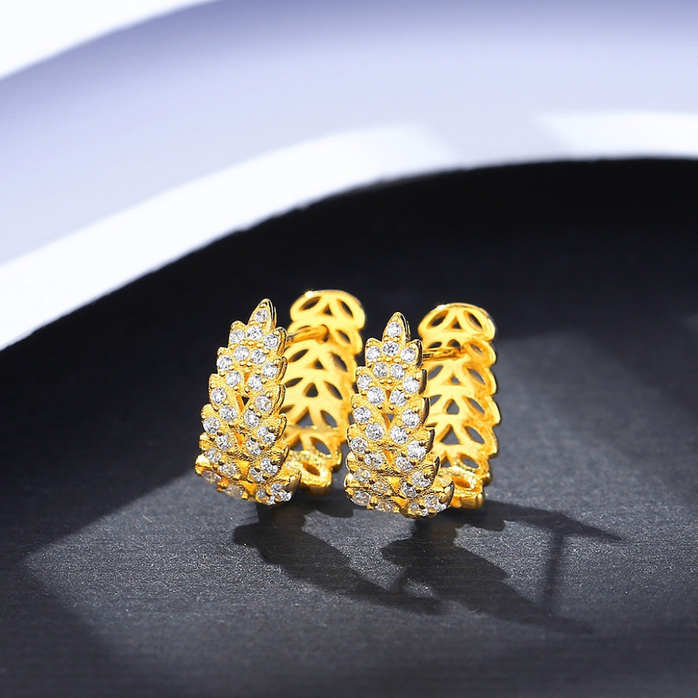 Gold earrings with intricate design on a dark surface.