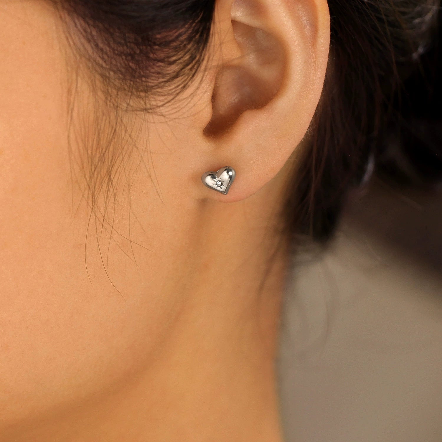 Heart-shaped earring worn by a person from SKADIS Jewelry