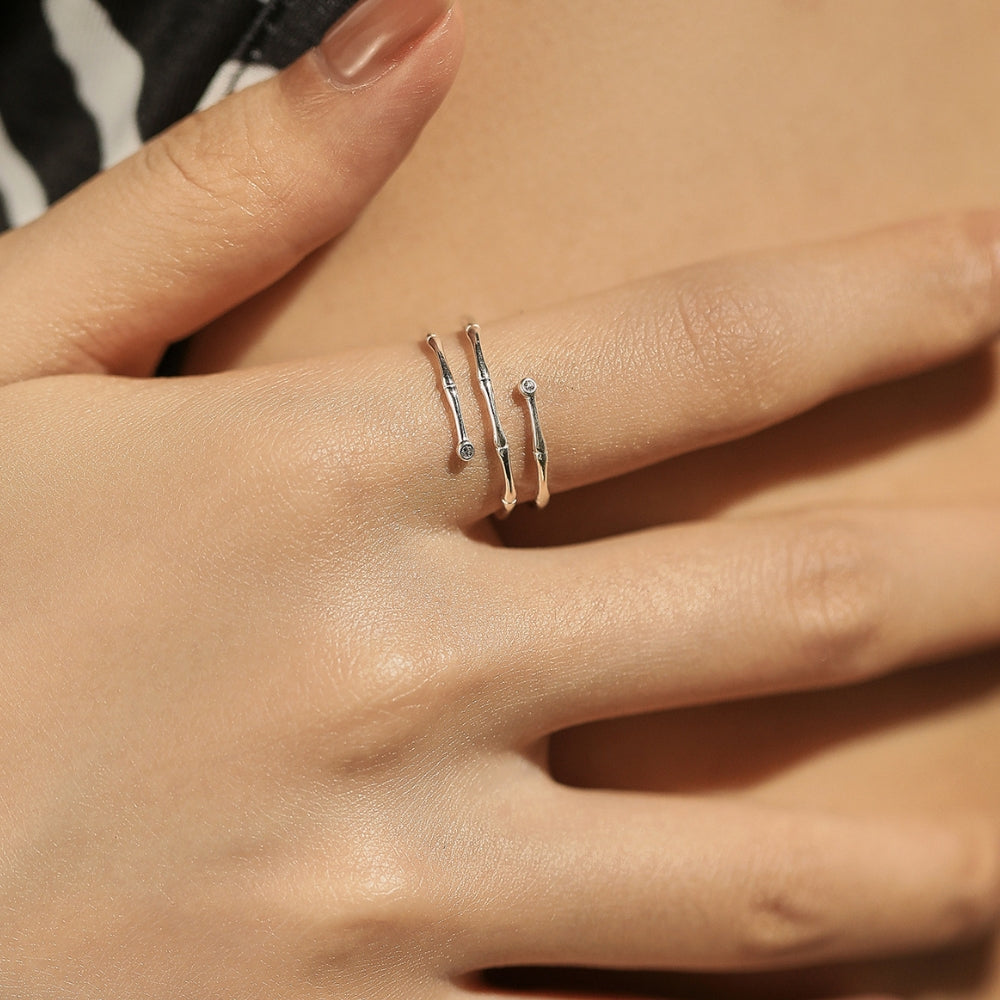 Hand wearing silver ring on a neutral background