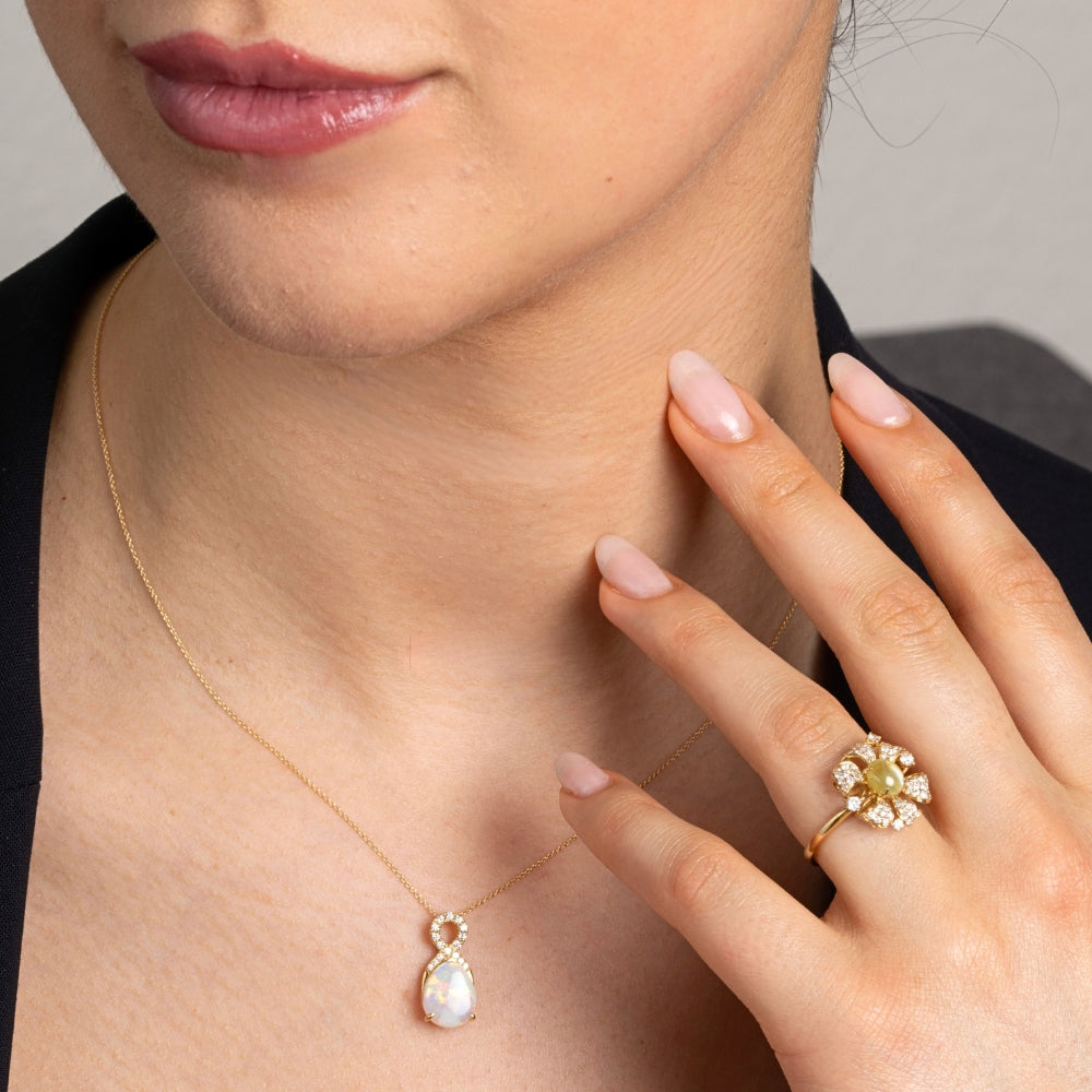 Close-up of a person wearing a gold necklace and ring with a flower design.