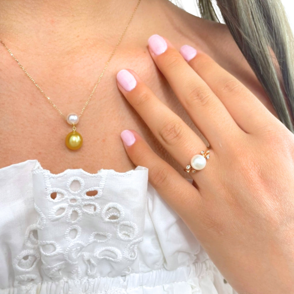 Pearl necklace and ring on a person wearing a white lace top.