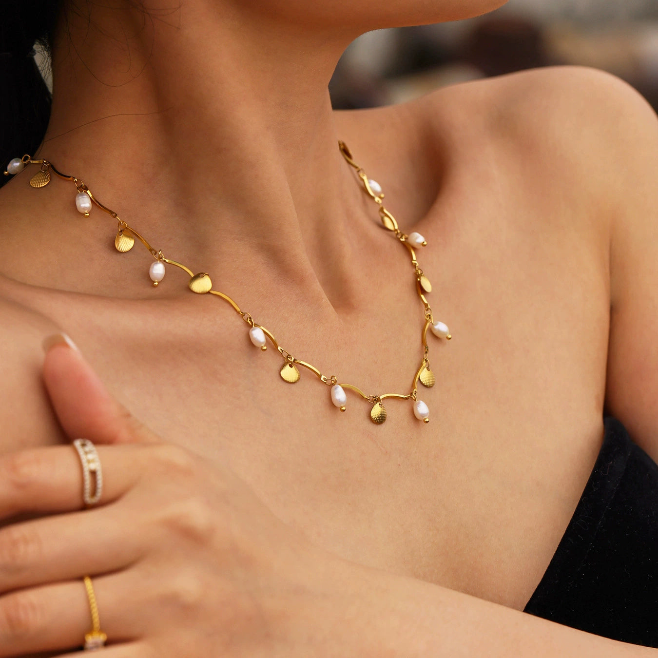 Gold necklace with heart and leaf designs worn by a person, skadis jewelry
