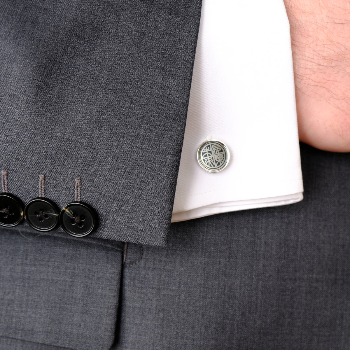 Close-up of a gray suit with a cufflink on a white shirt SKADIS Jewelry