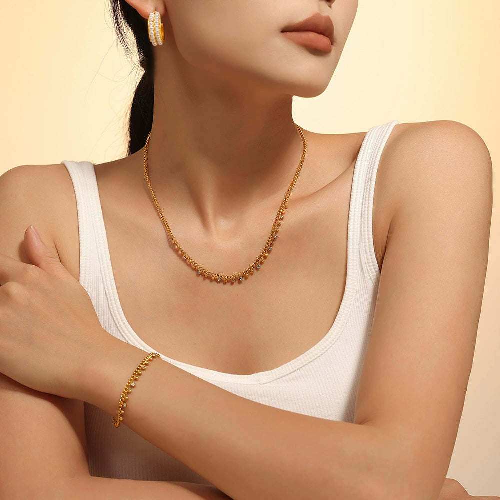 Woman wearing a gold necklace, bracelet, and earrings