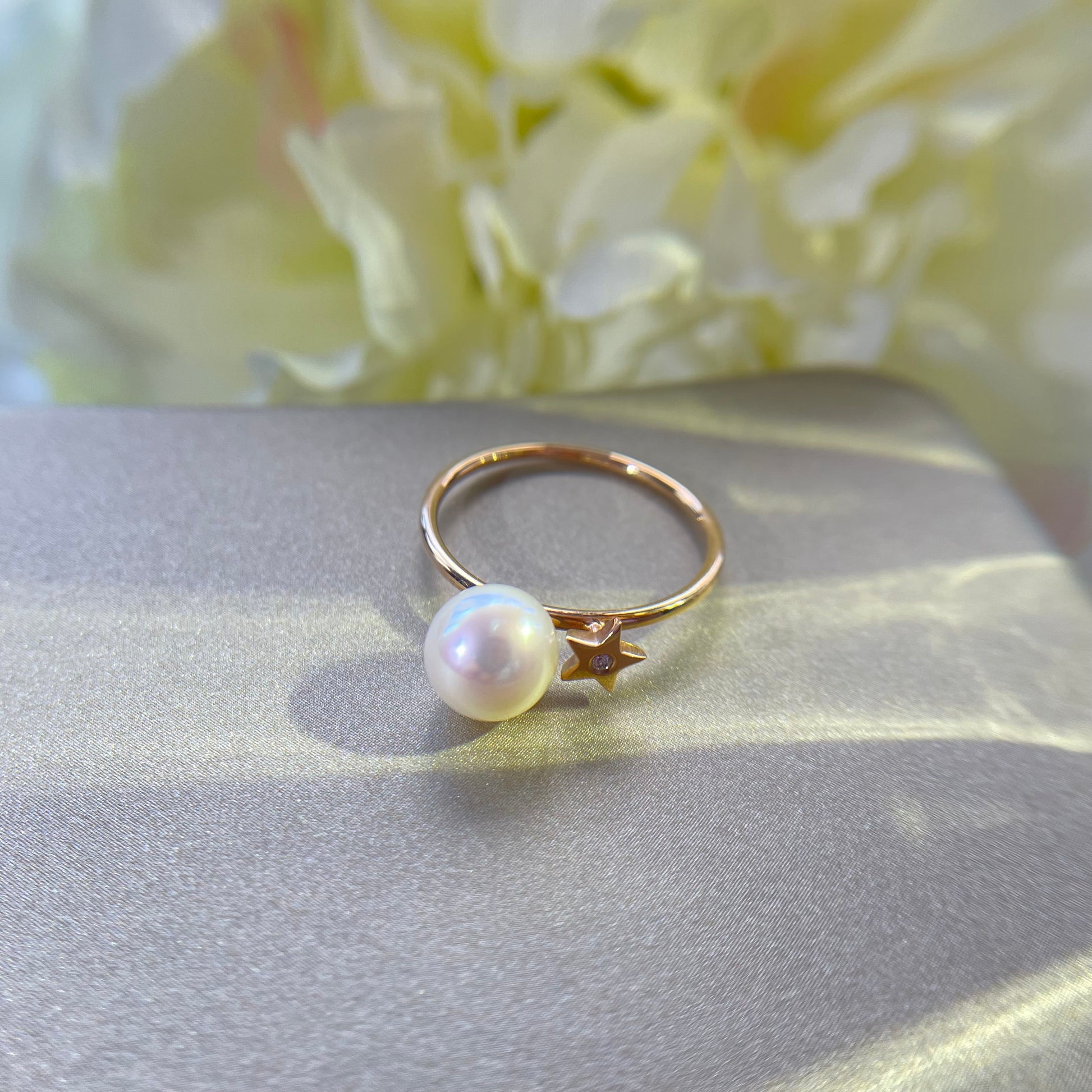 Gold ring with a pearl on a gold surface with a floral background