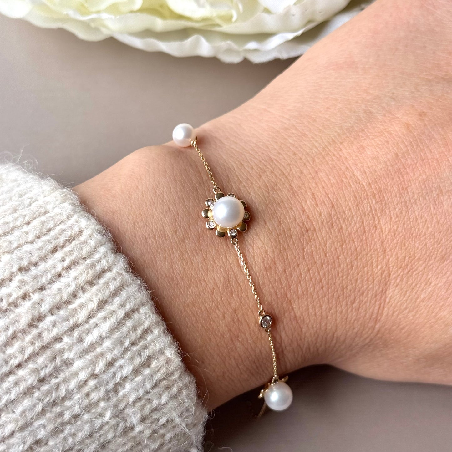 Pearl bracelet on a wrist with a neutral background.