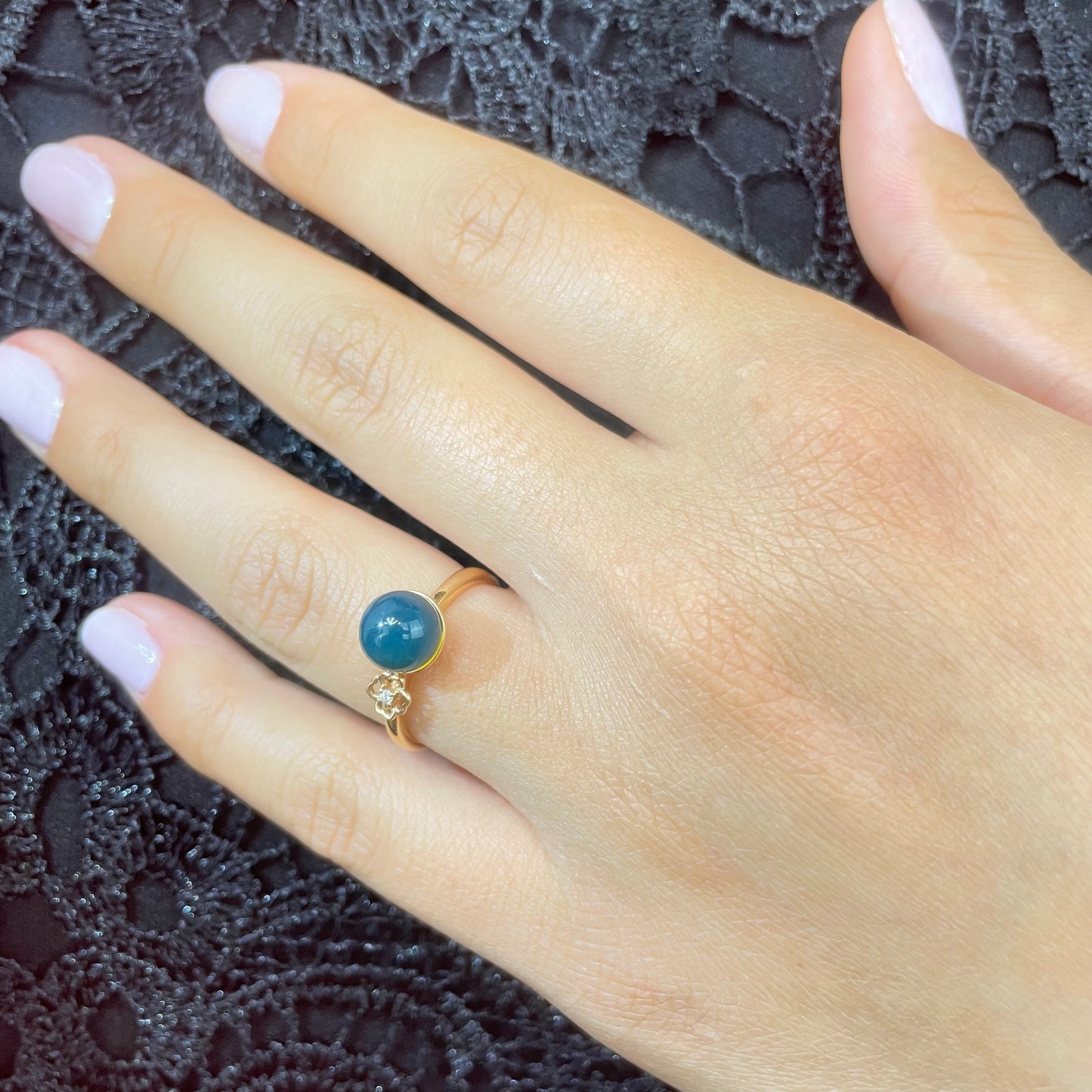 A hand wearing natural blue amber ring in 18k gold from SKADIS Jewelry Copenhagen.