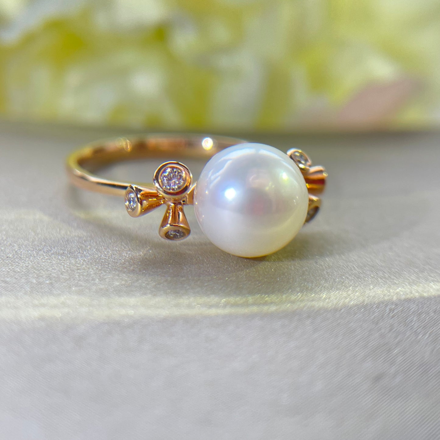 Pearl ring with diamonds on a light gold fabric background