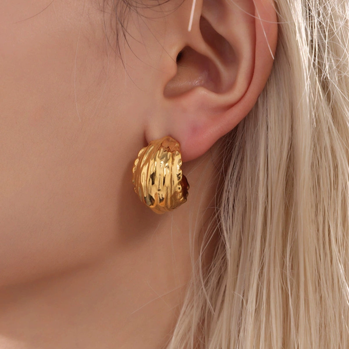 Gold hoop earring from SKADIS worn by a person with blonde hair.