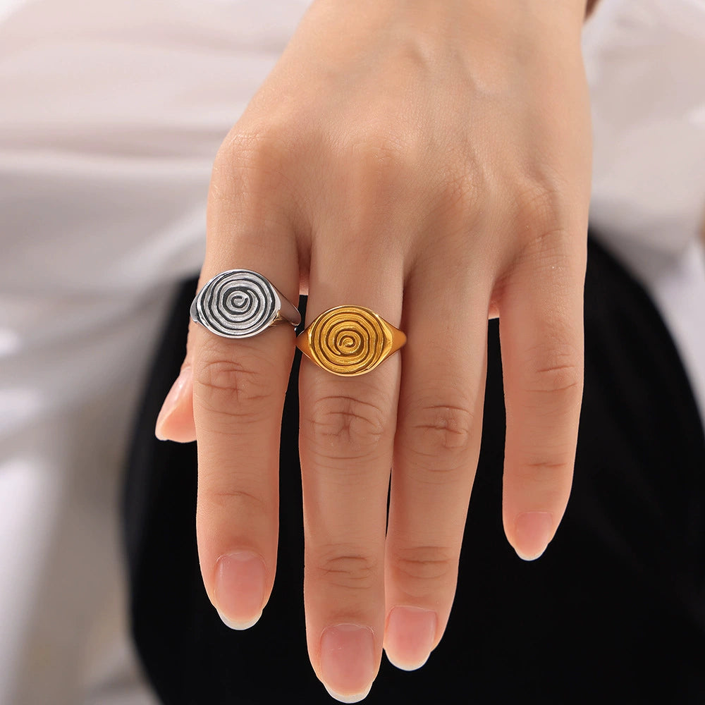Hand wearing two rings with spiral designs from SKADIS Jewelry
