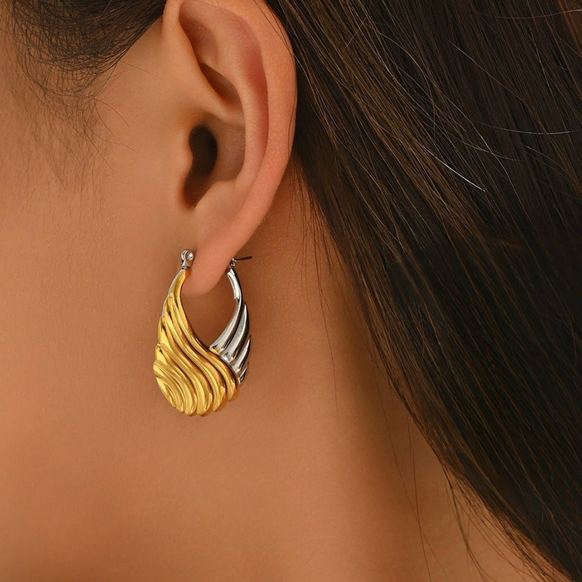 Gold and silver hoop earrings worn by a model from SKADIS Jewelry