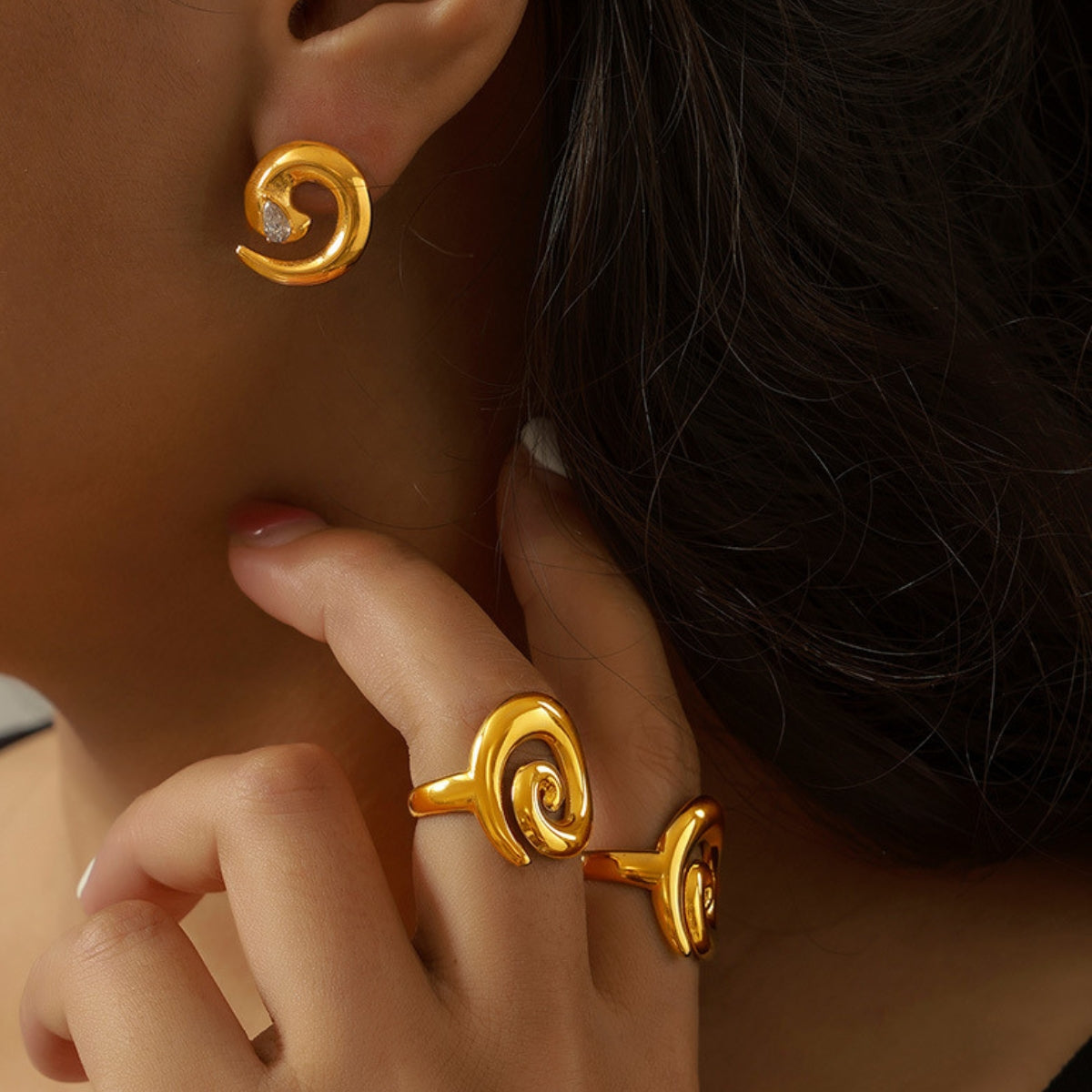 Close-up of a person wearing gold earrings and a matching ring - SKADIS Jewelry