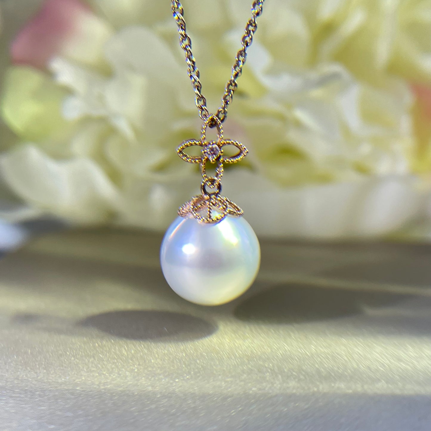 South sea pearl necklace with a gold bow pendant on a soft background.