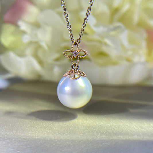 South sea pearl necklace with a gold bow pendant on a soft background.