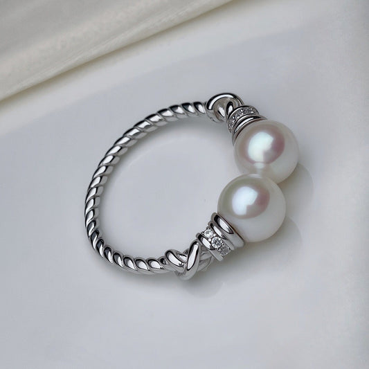 Silver ring with two pearls on a light background