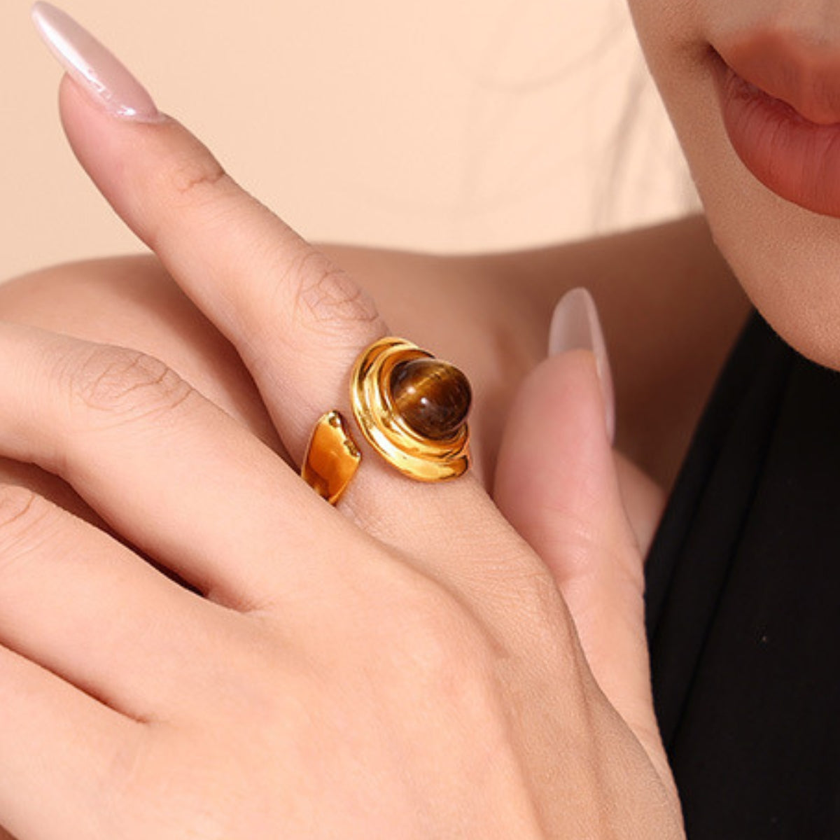 Gold ring with a tiger's eye stone on a hand from SKADIS Jewelry
