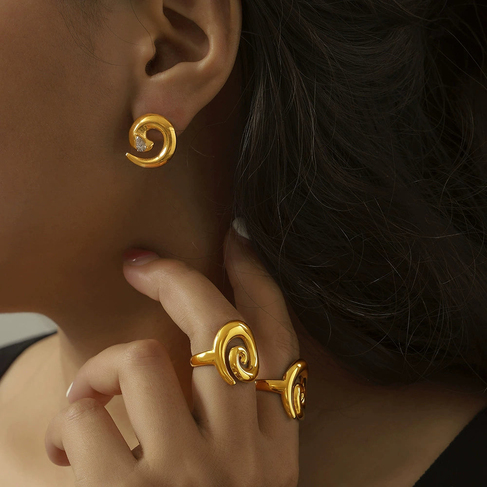 Model wearing gold spiral earrings and ring from SKADIS Jewelry