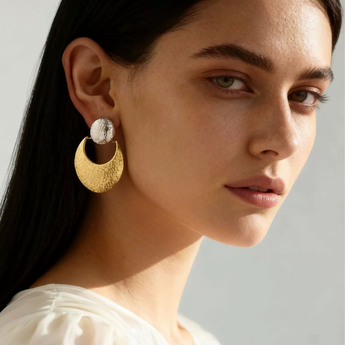 A woman wearing gold hoop earrings from SKADIS Jewelry