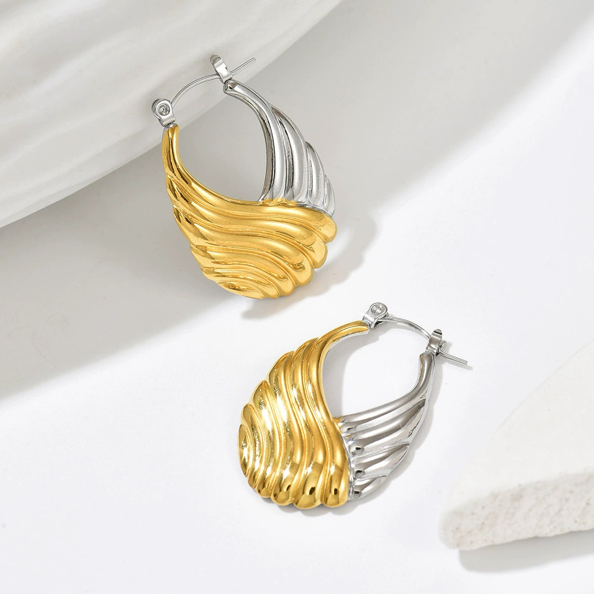 Two gold and silver hoop earrings from SKADIS Jewelry