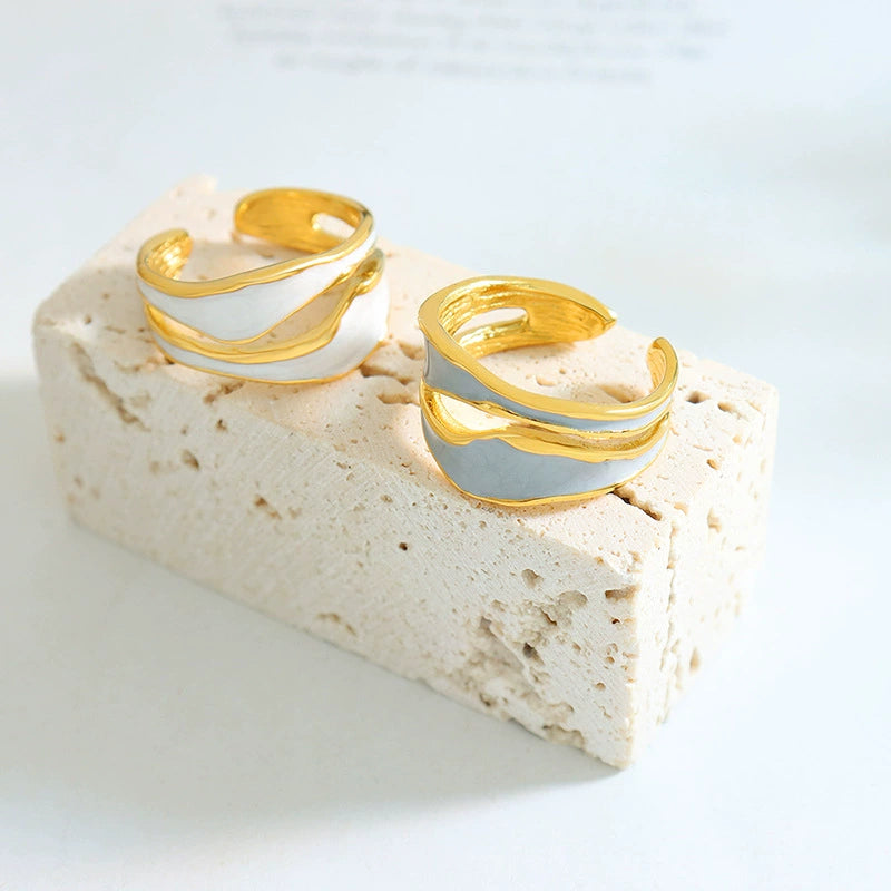 Two gold and silver rings on a beige stone surface - SKADIS Jewelry