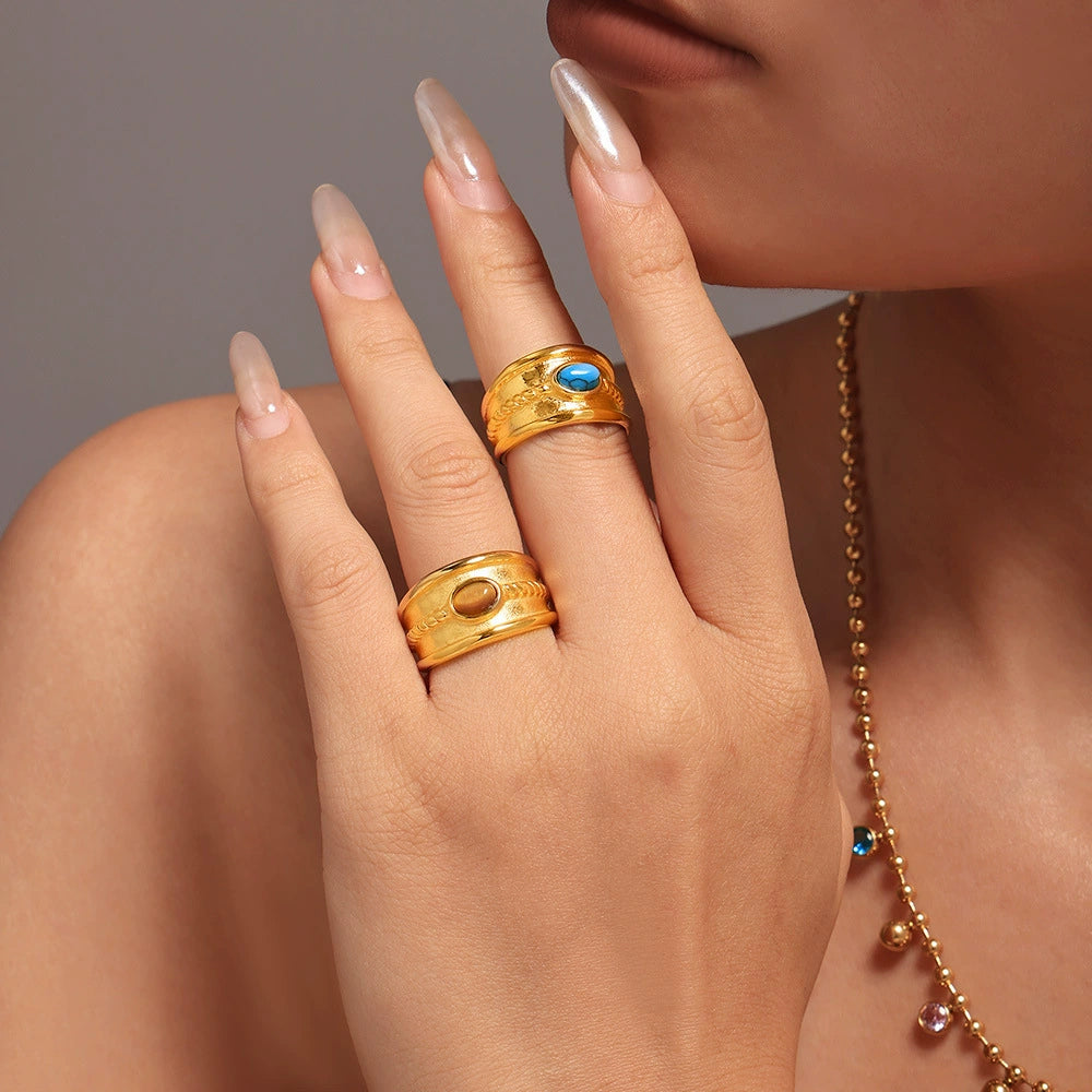 Hand wearing two gold rings with colored stones from SKADIS Jewelry