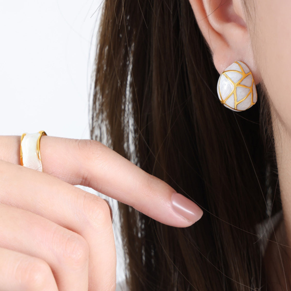 A person wearing a gold and white earring - SKADIS Jewelry